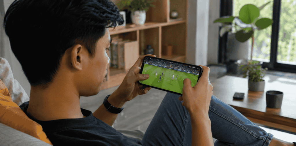 Person plays a football game on a mobile phone while sitting in a chair